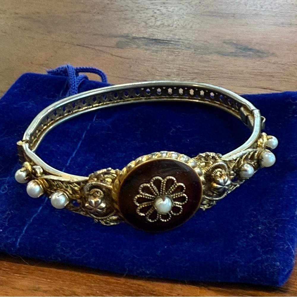 Vintage gold tone filigree hinged bangle bracelet with enamel and pearls